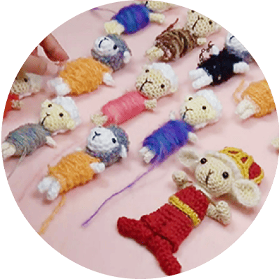 ②キャラクターを動かす(コマ撮り)、の工程の画像(複数の編みぐるみが撮影台に並んでいる画像)